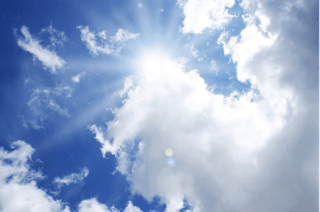 Bright sun shining through clouds in blue sky, symbolizing natural vitamin D source
