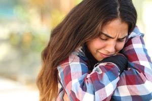 Sad young woman outdoors hugging herself, mental health and emotional support concept