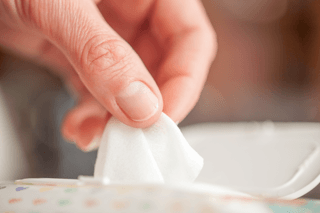 Hand picking up disinfectant wipe from container, household cleaning concept