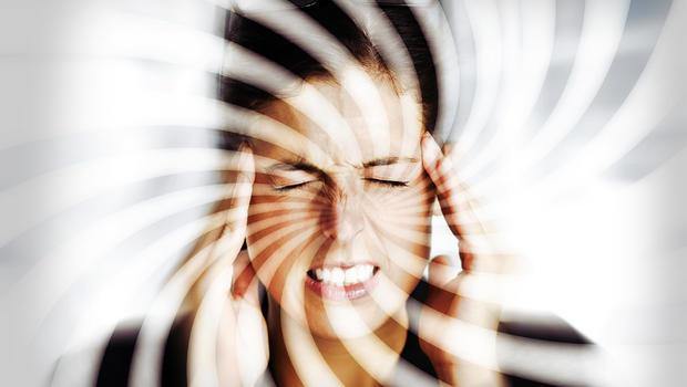 Woman experiencing vertigo or dizziness, holding temples, with swirling visual effect