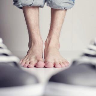 Bare feet on floor with rolled-up jeans, sneakers in foreground, health and wellness concept
